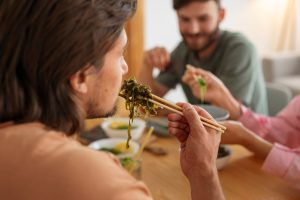 Group of friends gathered around a table enjoying bowls of noodles.