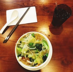 Vietnamese noodles served with fresh lettuce on a wooden table.